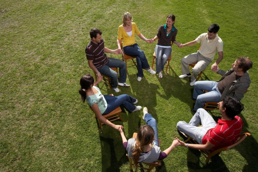 People sitting in a circle while holding hands